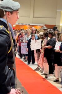 military color guard and people holding signs welcoming home veterans