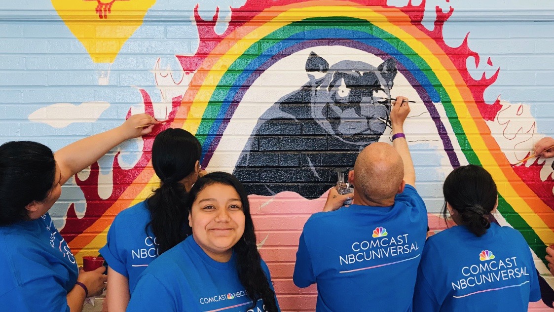 Comcast Cares Day volunteers paint a mural.